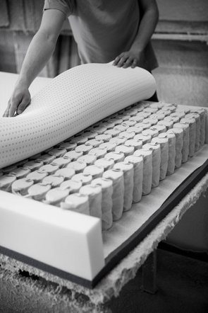 A craftsman laying a comfort layer over a mattress core